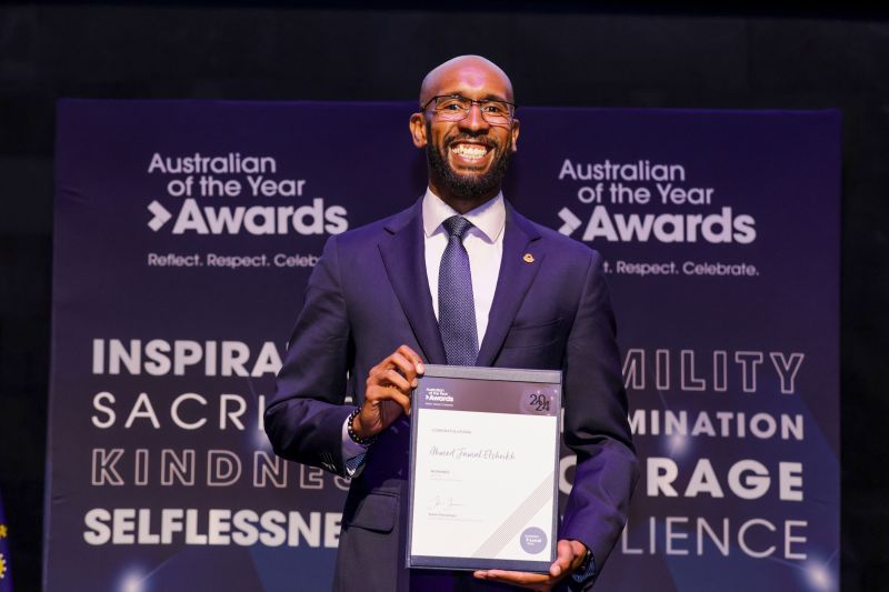 Jamal Elsheikh A. on stage at the Australian of the Year Awards holding a framed certificate