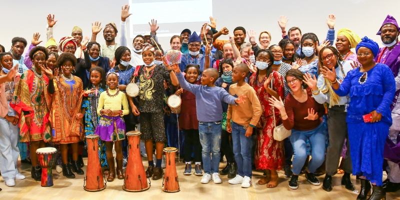 Group photo of over 50 people from the Yoruba community. Some are holding instruments or have their arms in the air